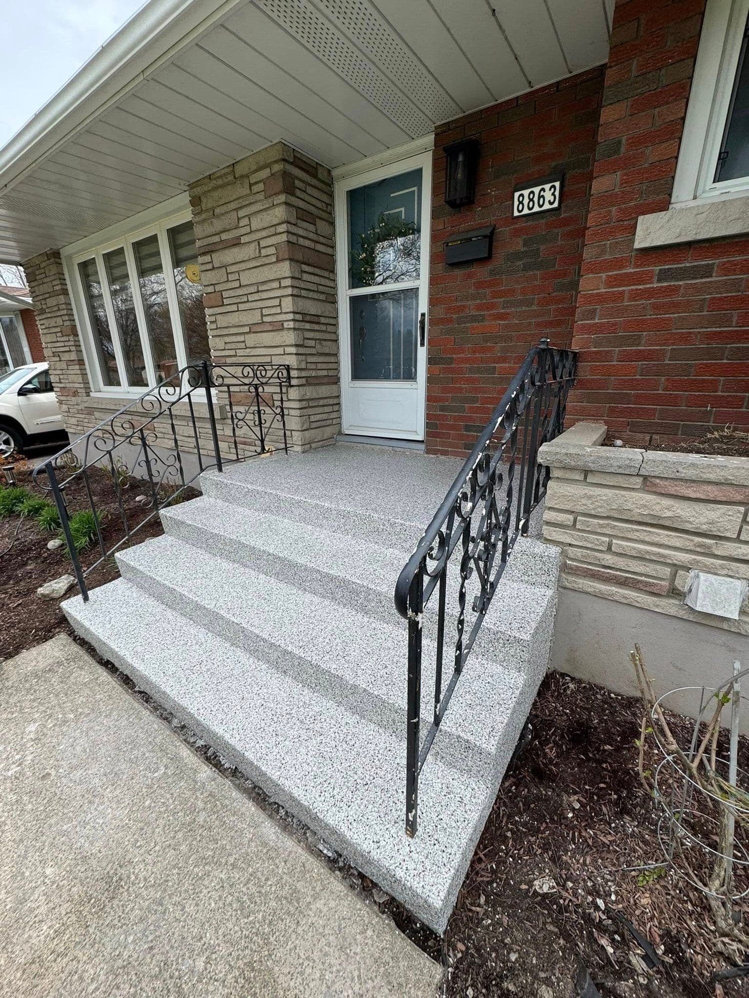 Grey flake epoxy front steps with a wrought-iron railing